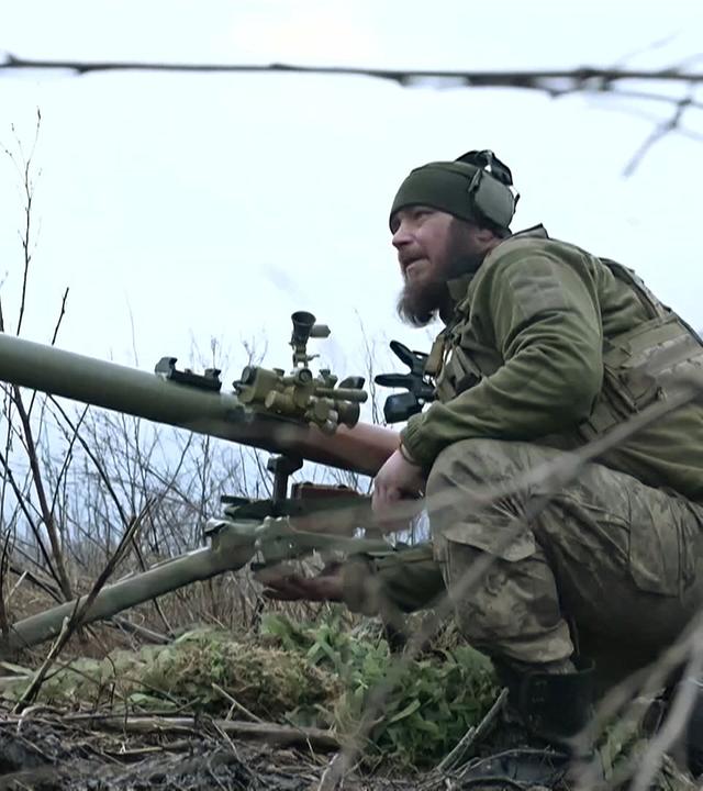 Ein Soldat hockt hinter einem Stacheldraht