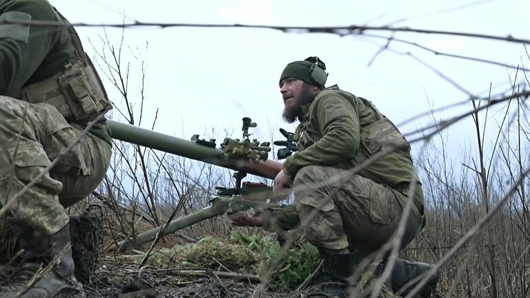 Ein Soldat hockt hinter einem Stacheldraht