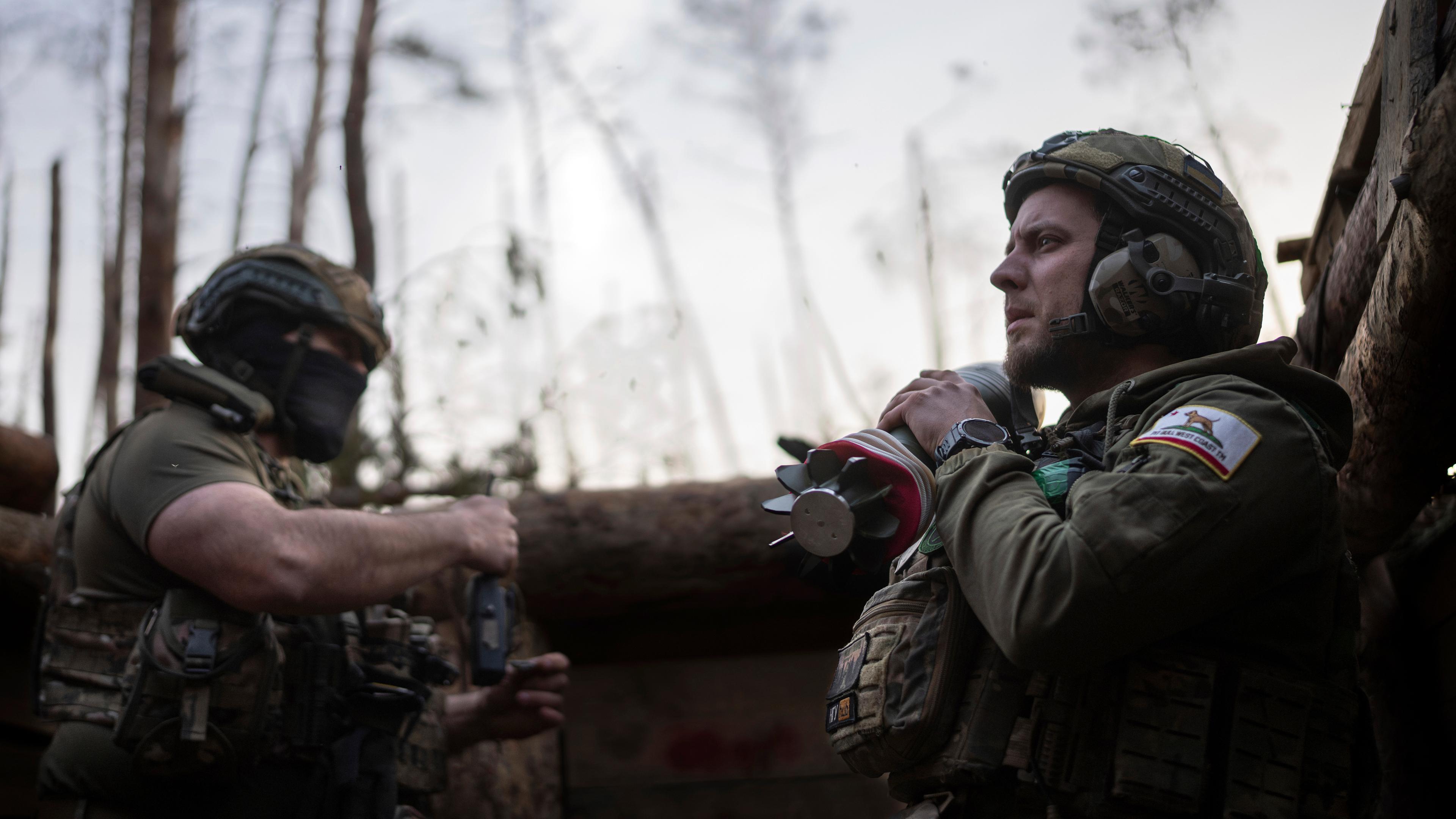 Archiv: Ein ukrainischer Soldat der Asow-Brigade, bekannt unter dem Rufnamen Chaos, rechts, trägt eine Mörsergranate, während er auf einen Feuerbefehl wartet. 