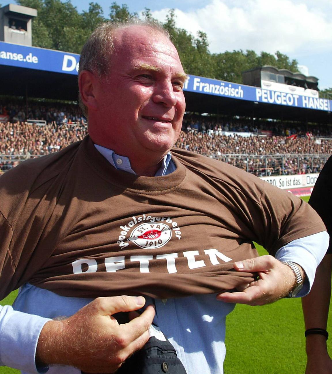 Manager Uli Hoeneß (Bayern) streift sich beim Benefizspiel zur Lizenzsicherung des FC St. Pauli ein Retter T-Shirt über 