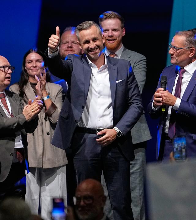 Ulrich Siegmund von der AfD streckt seinen Daumen nach dem Wahlsieg hoch aus und lächelt. Er ist umgeben von anderen AfD-Parteimitgliedern sowie Alice Weidel und Tino Chrupalla.