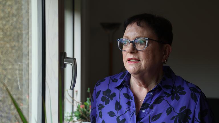 Ulrike Dierkes steht in einem Wohnzimmer und schaut aus dem Fenster.