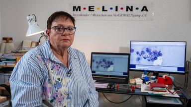 Ulrike Dierkes sitzt in ihrem Büro und schaut in die Kamera. Im Hintergrund stehen Bildschirme auf einem Schreibtisch, darüber hängt das Vereinslogo "Melina".