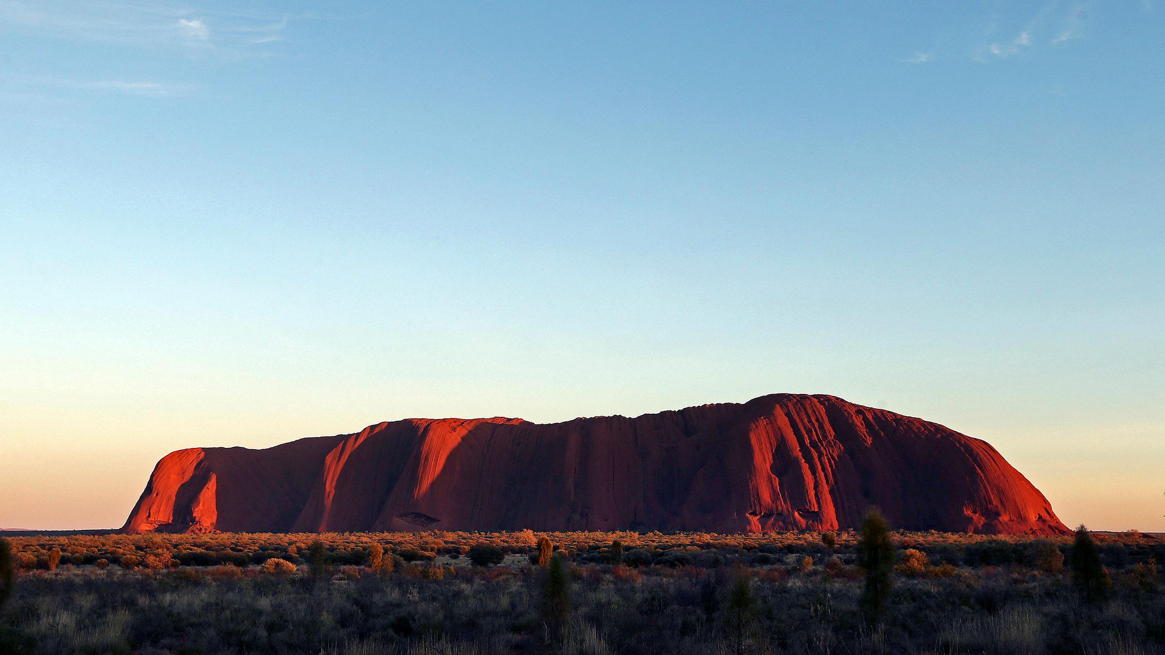 Der Uluru in Australien leuchtet in rot während des Sonnenaufgangs