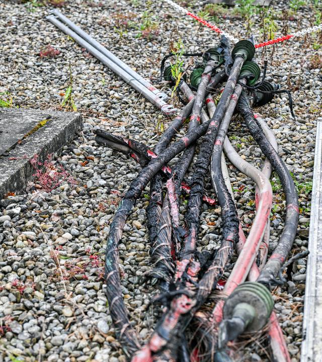 Mehrere verkokelte Kabel liegen nach dem Brand in einem Umspannwerk in Reutlingen auf dem Boden. Die Ermittler gehen von Brandstiftung aus.