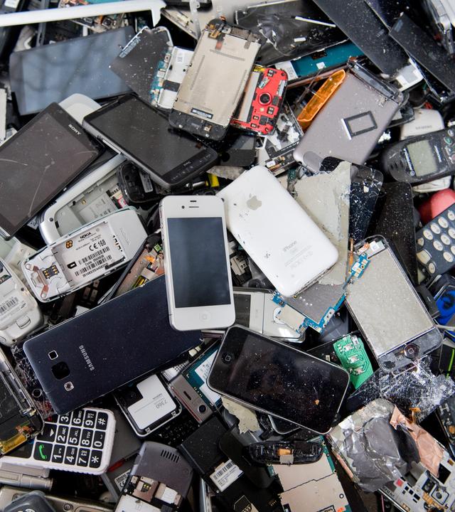 Alte Handys und Smartphones liegen in einem Container.