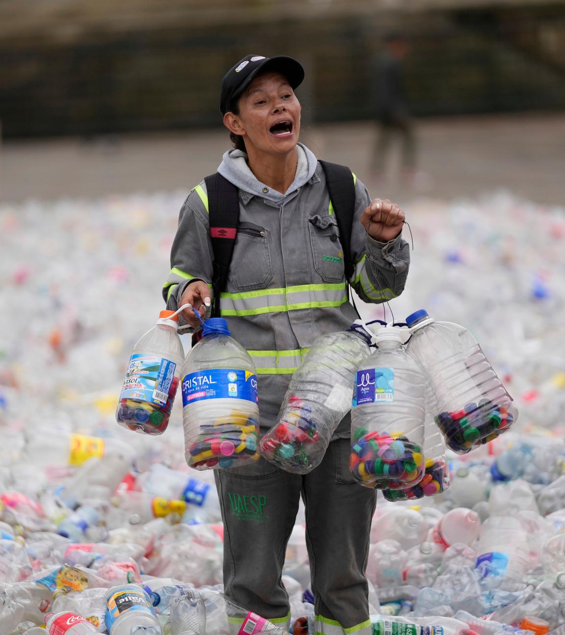 Symbolbild: Eine Recyclerin watet durch Plastikflaschen, als Recyclingarbeiter gegen die niedrigen Preise protestieren, die Unternehmen für recycelte Materialien zahlen. 