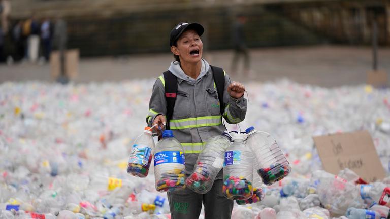 Symbolbild: Eine Recyclerin watet durch Plastikflaschen, als Recyclingarbeiter gegen die niedrigen Preise protestieren, die Unternehmen für recycelte Materialien zahlen. 