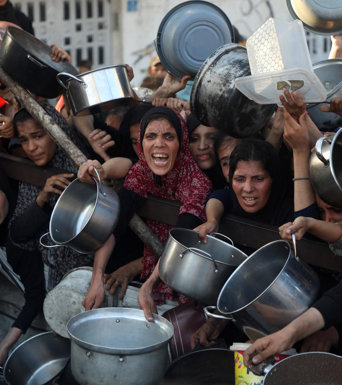Palästinenser warten mit Töpfen und anderen Gefäßen an einer Essensausgabe in Gaza-Stadt.