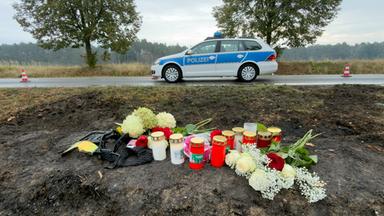 Unfallstelle mit Kerzen und Blumen, im Hintergrund ein Polizeiauto