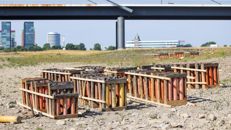 Die Abschussvorrichtungen für das Feuerwerk der Rheinkirmes stehen und liegen auf den Rheinwiesen.