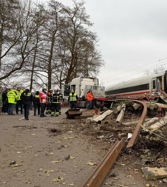 Rettungskräfte arbeiten an der Unfallstelle. In Hamburg-Harburg ist ein ICE gegen einen Sattelzug gefahren.