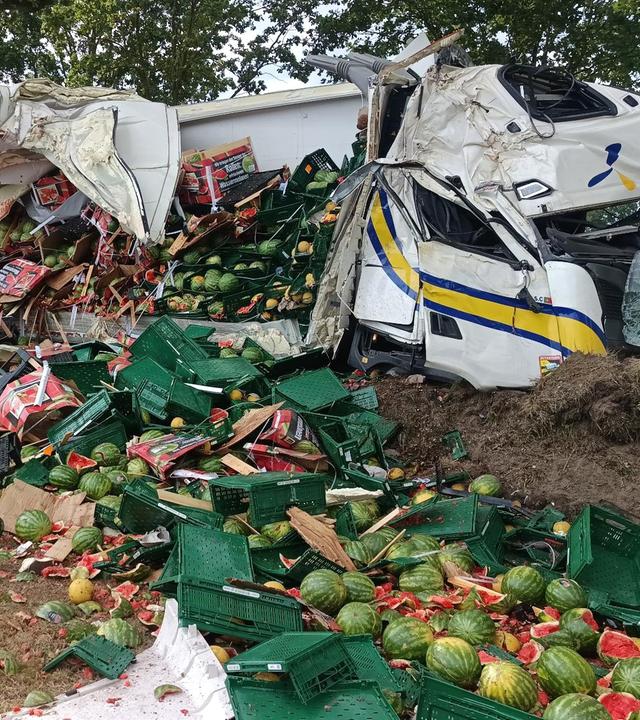 Melonen liegen neben der Fahrbahn auf einem Acker, nachdem ein Lkw gegen einen Baum geprallt ist.