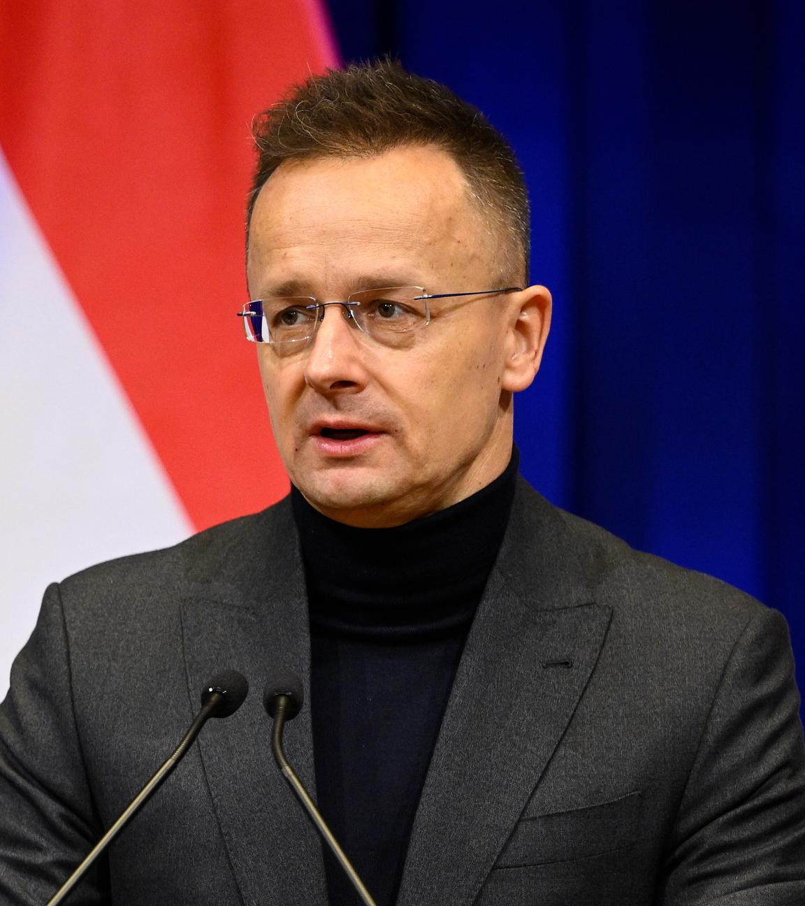 Der ungarische Minister für auswärtige Angelegenheiten und Handel, Peter Szijjarto bei einer Pressekonferenz in Budapest. Hinter ihm die unagrische Flagge.