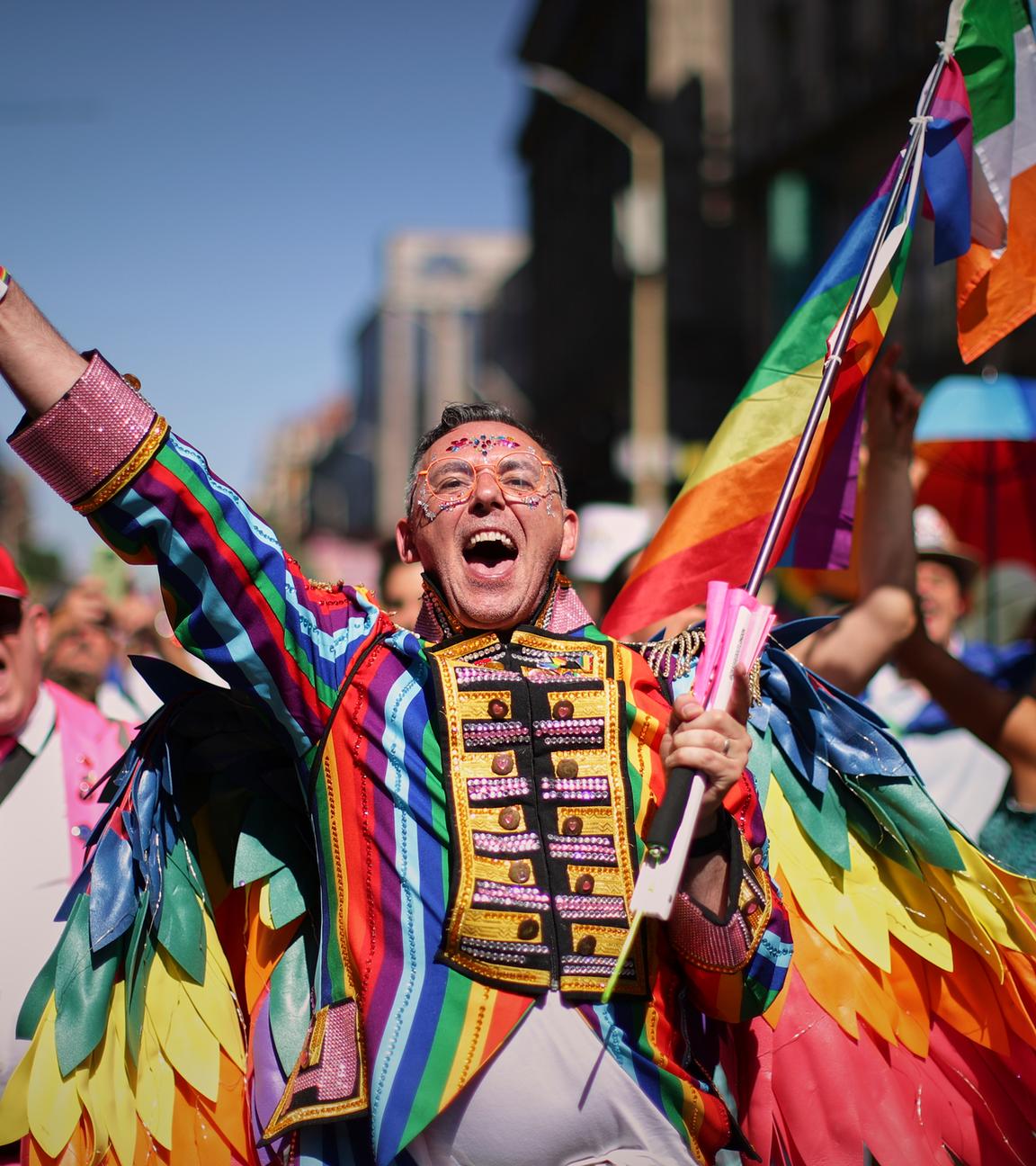 Ein bunt kostümierter Teilnehmer des Pride-Marsches in Budapest jubelt. 