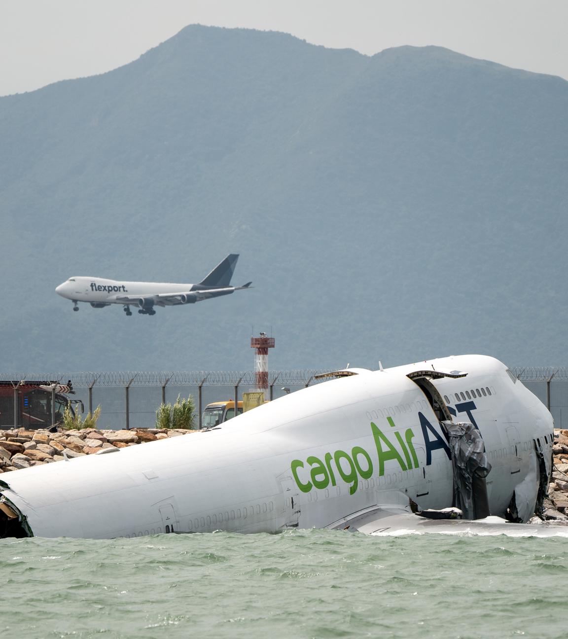 Ein Flugzeug, das neben einem Frachtflugzeug landet, liegt teilweise im Meer, nachdem es bei der Landung auf dem Hongkong International Airport am 19.10.2025 in Hongkong von der Landebahn abgekommen ist. 