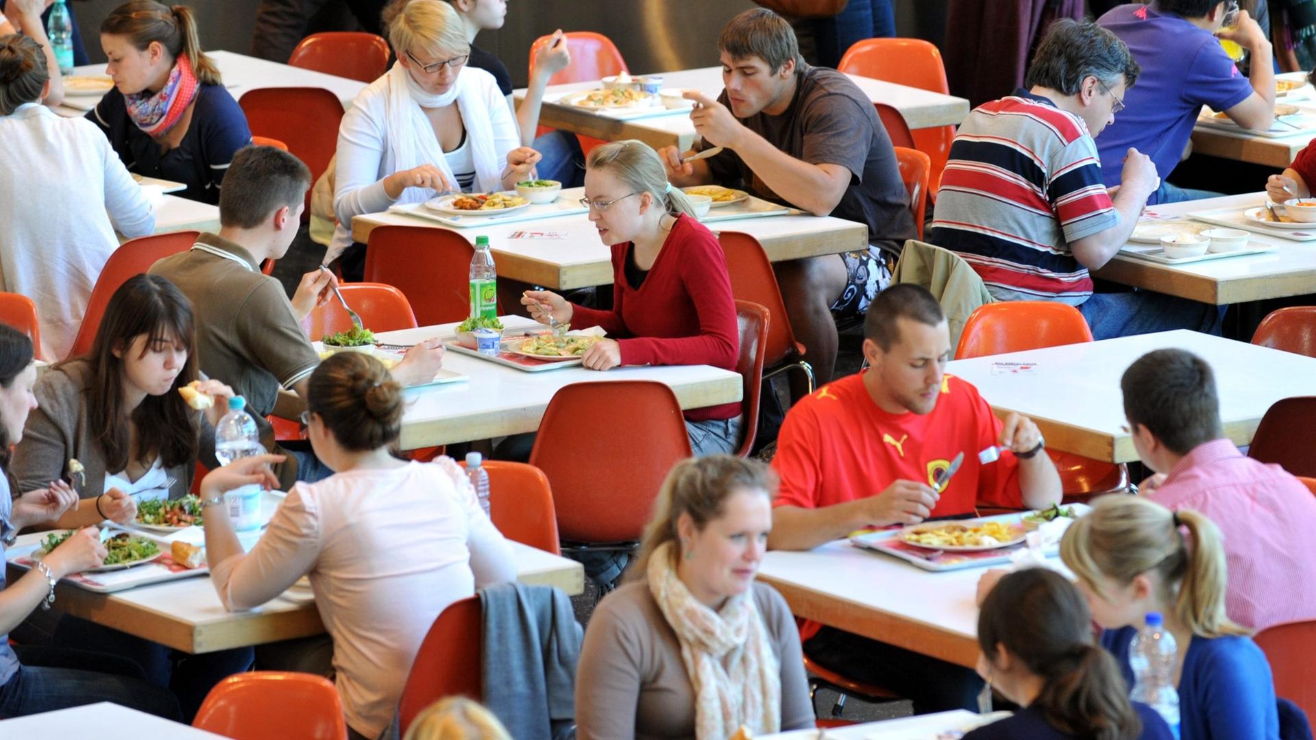 Studenten nehmen in der Mensa der Universität in Freiburg ihr Mittagessen ein