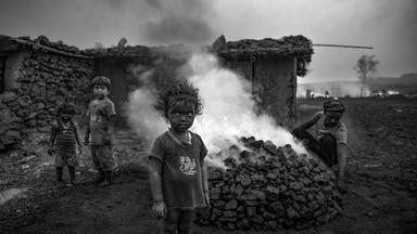 15.12.2025, Indien, ---: Kinder stehen in einem Kohlefeld von Jharia in Indien.