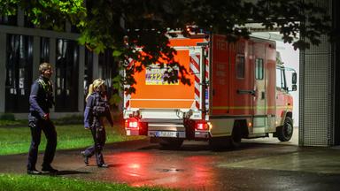 Polizisten laufen an einem ankommenden Rettungswagen vorbei, der eine deutsche Patientin in das Infektionszentrum der Uniklinik Düsseldorf bringt.