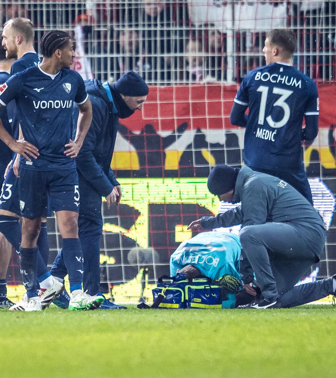14.12.2024, Fußball-Bundesliga, 1. FC Union Berlin - VfL Bochum: VfL-Torwart Patrick Drewes kauert nach einem Feuerzeug-Treffer auf dem Boden, um ihn herum Spieler vom VfL Bochum