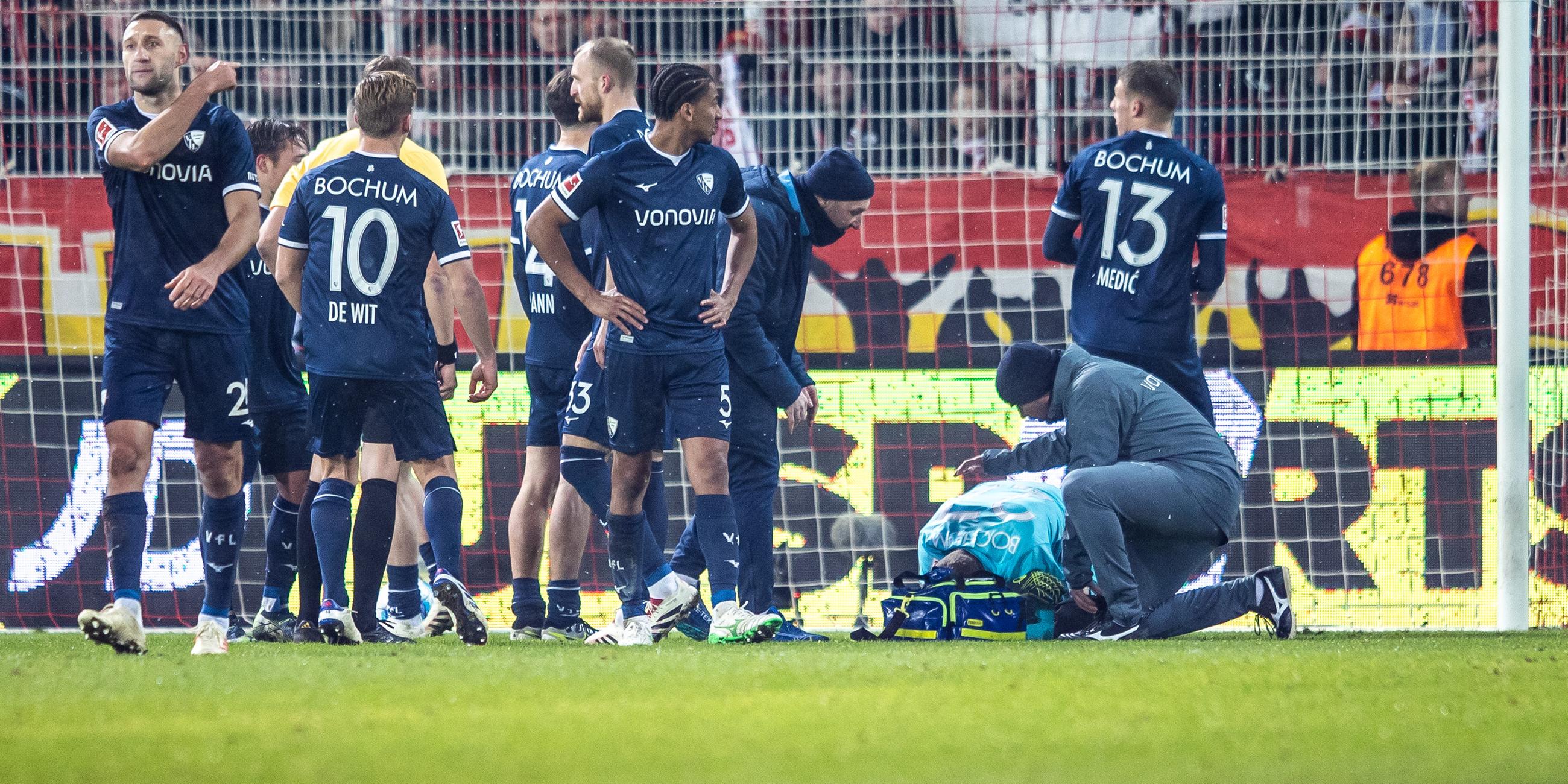 14.12.2024, Fußball-Bundesliga, 1. FC Union Berlin - VfL Bochum: VfL-Torwart Patrick Drewes kauert nach einem Feuerzeug-Treffer auf dem Boden, um ihn herum Spieler vom VfL Bochum