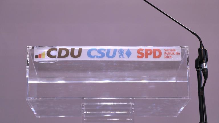 Rednerpult mit den Logos der Parteien CDU, CSU und SPD.
