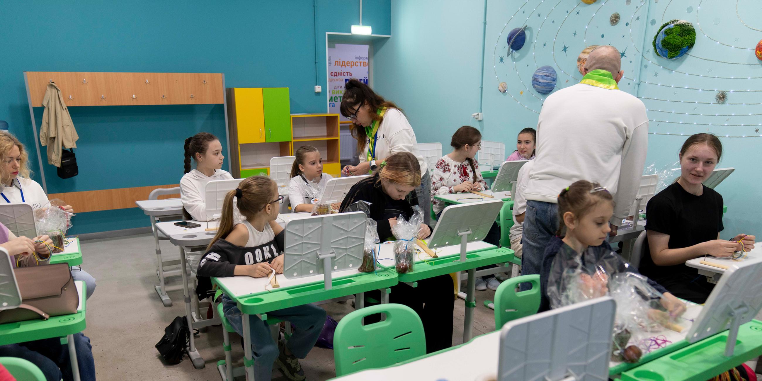 Schüler besuchen am Osterwochenende (20.04.2025) eine neu errichtete unterirdische Schule. Viele tragen traditionelle ukrainische Wyshywanka. Wegen andauernden russischen Beschusses bieten die Schutzräume einen sicheren Lernort.
