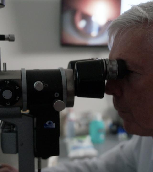 Augenarzt untersucht bei einem Patienten die Sehstärke mit einem Refraktor