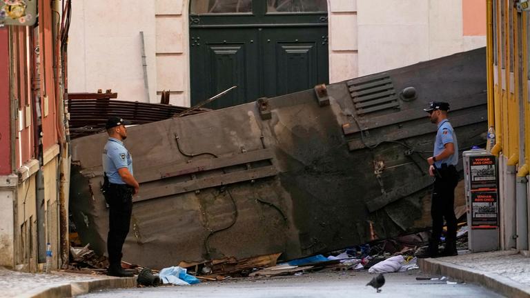04.09.2025, Portugal, Lissabon: Polizeibeamte sperren den Bereich ab, in dem eine Straßenbahn für Touristen entgleist ist.