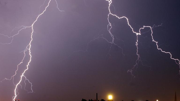 Archiv: Blitze zucken in der Nacht über einer Stadt