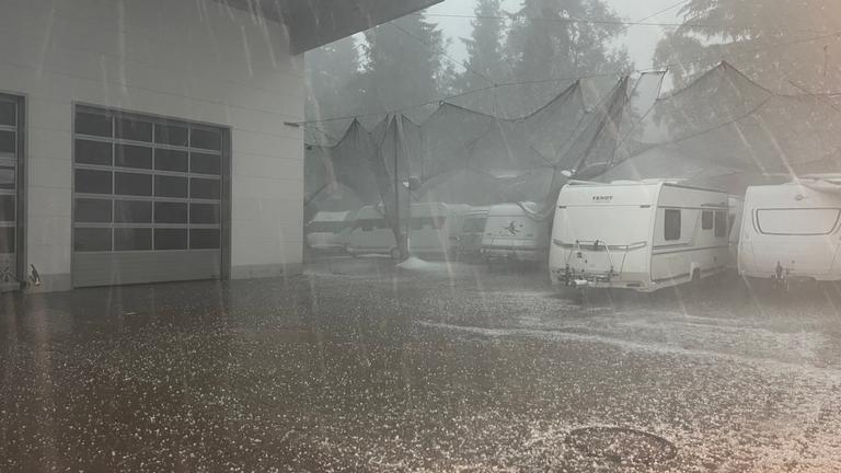 Bayern, Immenstadt: Campingwagen stehen unter Hagelnetzen bei einem schweren Unwetter mit Hagel.