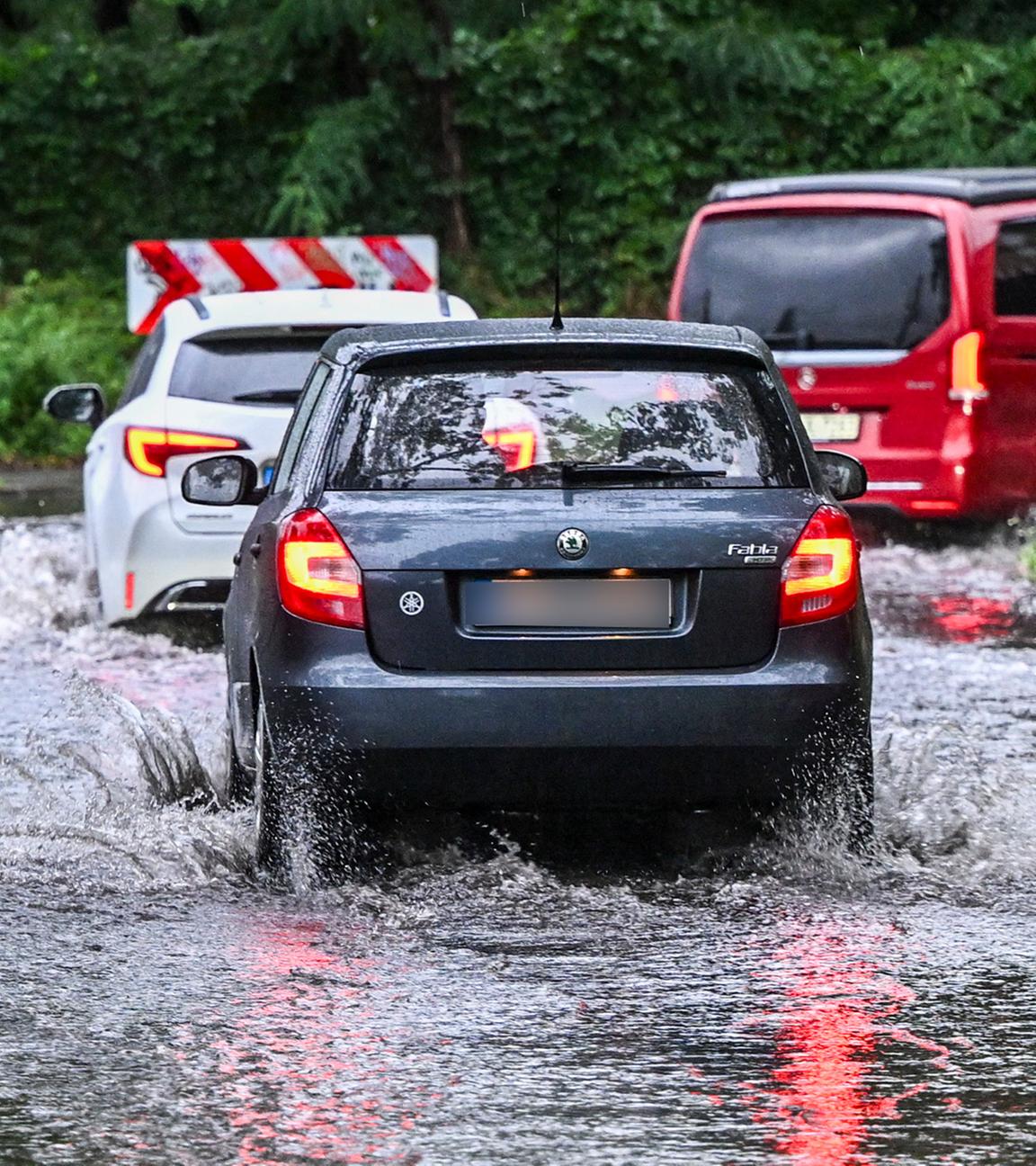 Nach starken Regenfällen bahnen sich Autos am 21. Juli 2025 in der Wallensteinstraße in Karlshorst ihren Weg durch eine überspülte Straße.