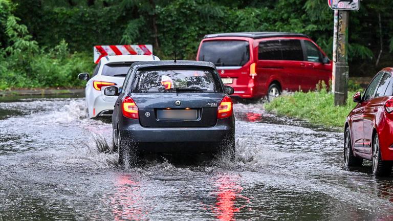 Nach starken Regenfällen bahnen sich Autos am 21. Juli 2025 in der Wallensteinstraße in Karlshorst ihren Weg durch eine überspülte Straße.