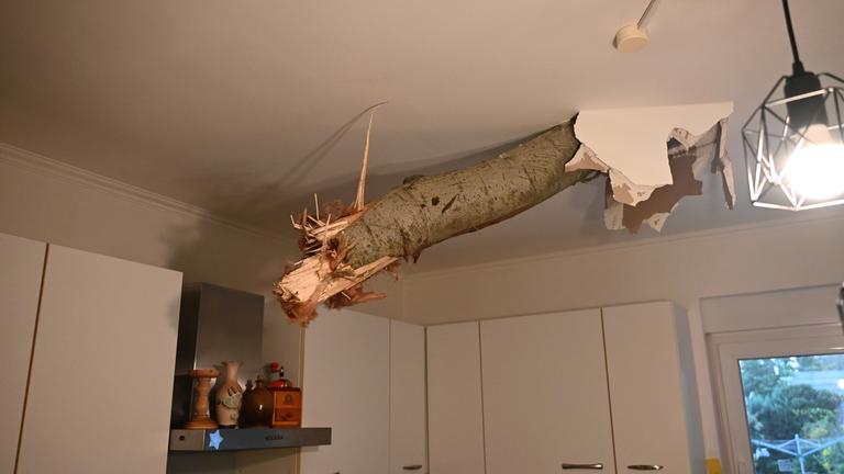 Ein Baumstamm ragt nach einem Unwetter in Fürstenwalde-Süd aus der Decke in der Küche eines Wohnhauses. 
