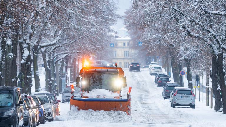 Ein Schneeräumfahrzeug fährt bei Schneefall über die Autobahn A8
