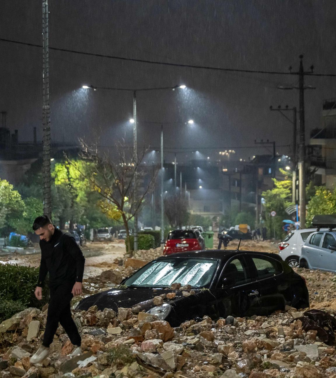 Ein Mann geht an einem mit Trümmern bedeckten Auto vorbei.