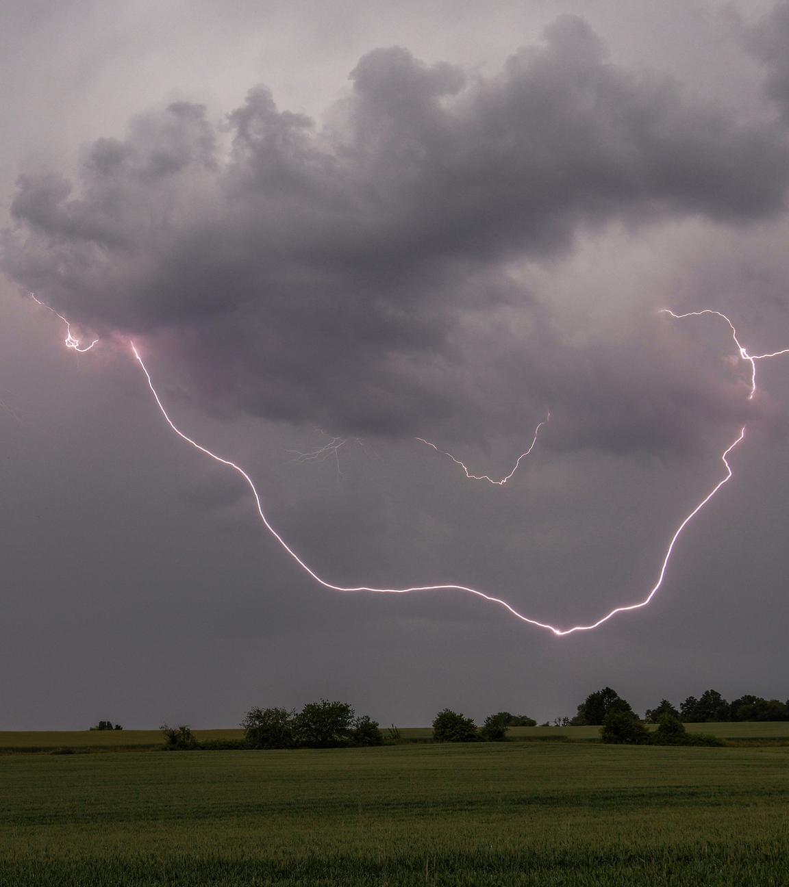 Der Blitz eines Gewitters ist am Nachmittag über einem Feld bei Oberursel-Oberstedten zu sehen. 