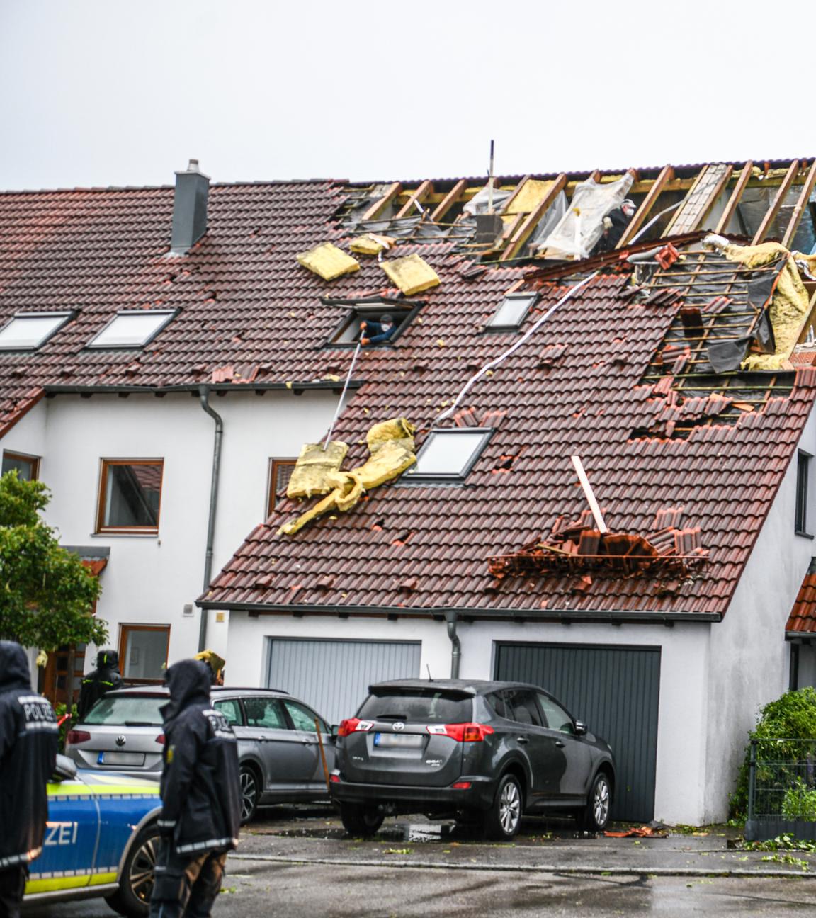 Einsatzkräfte von Feuerwehr und Polizei sind im Stadtteil Donaustetten im Einsatz, nachdem durch das Unwetter das Dach eines Reihenhauses stark beschädigt wurde. Am 04.06.2025, Baden-Württemberg, Ulm