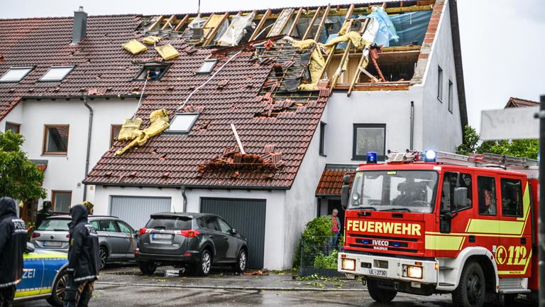 Einsatzkräfte von Feuerwehr und Polizei sind im Stadtteil Donaustetten im Einsatz, nachdem durch das Unwetter das Dach eines Reihenhauses stark beschädigt wurde. Am 04.06.2025, Baden-Württemberg, Ulm