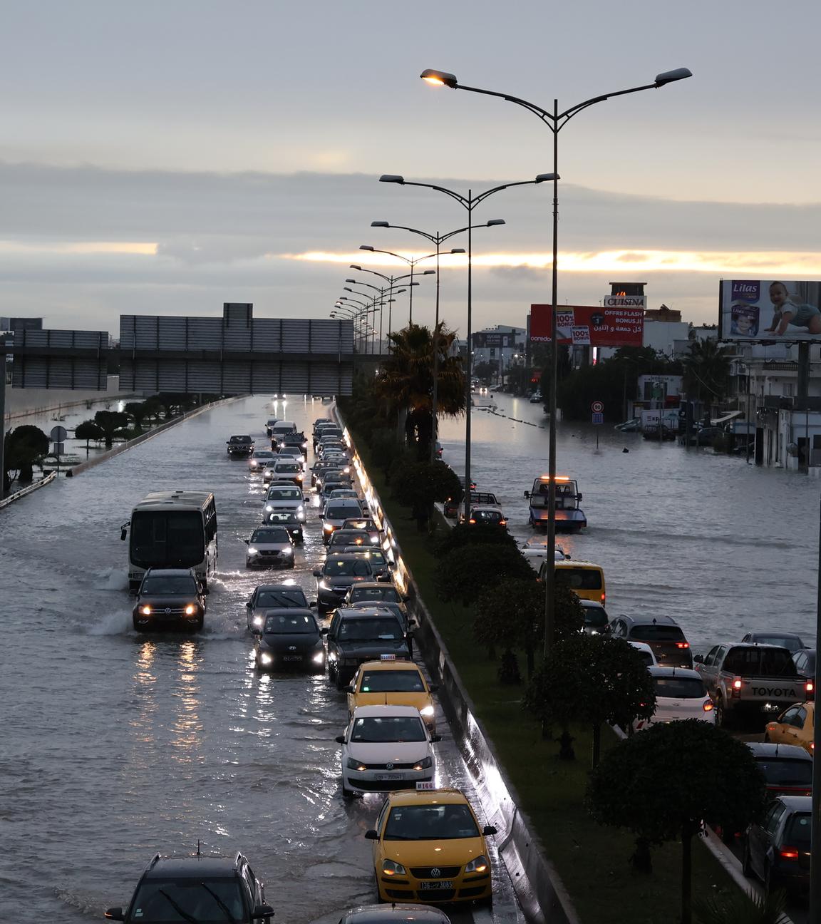 Fahrzeuge fahren durch eine überflutete Straße.