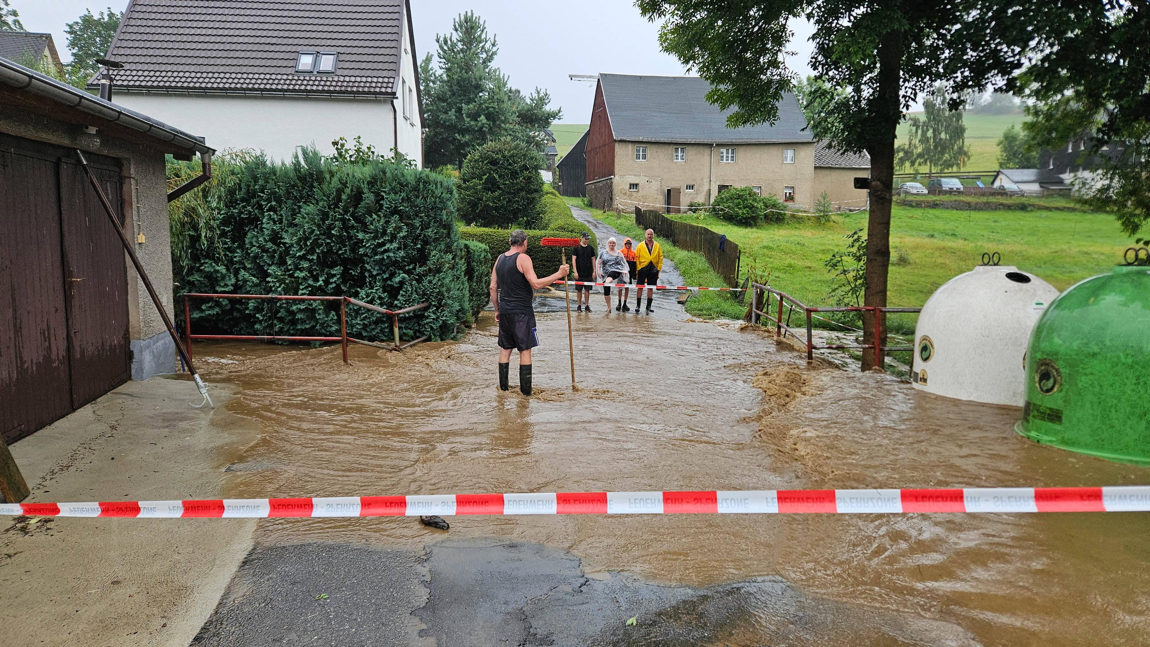 Teile Sachsen sind überflutet worden, sowie auf dem Bild erkennbar. Menschen stehen im Hochwasser.