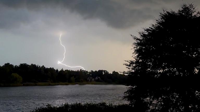 Schleswig-Holstein, Kosel: Ein Blitz zuckt während eines Unwetters über dem Langsee in der Nähe von Eckernförde.