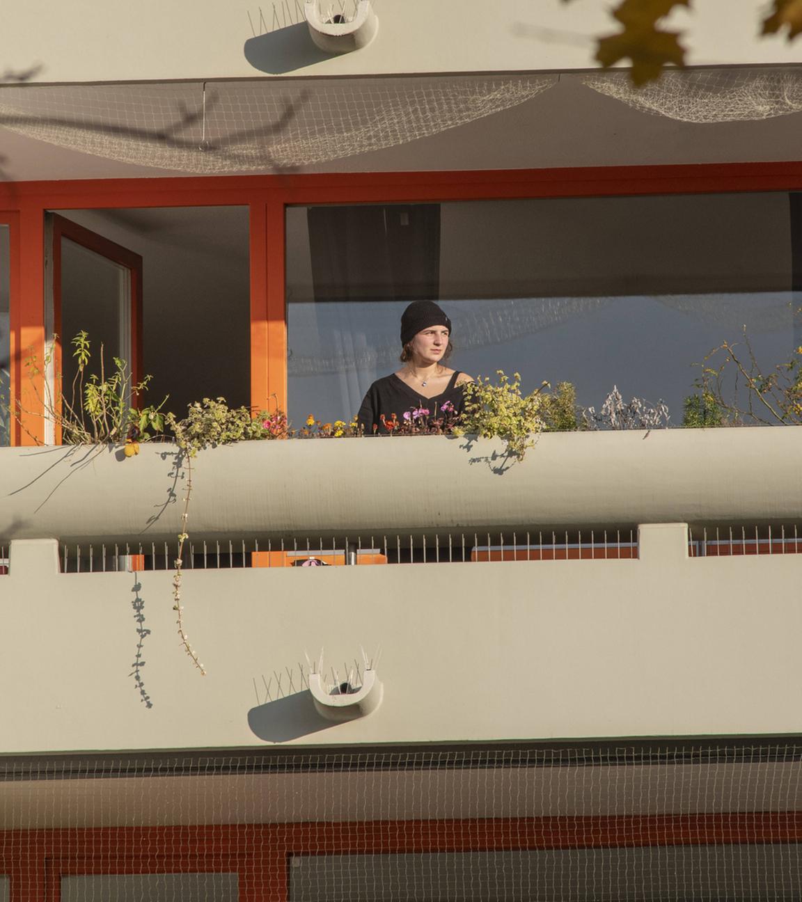 Eine Frau steht auf ihrem Balkon