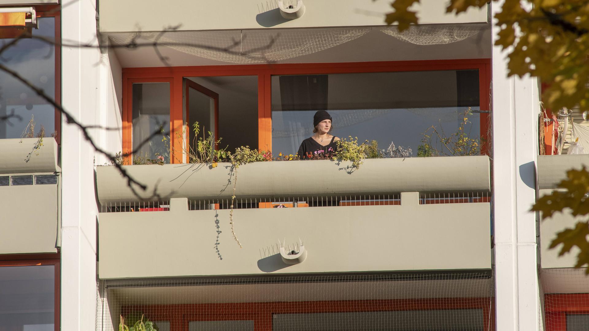 Eine Frau steht auf ihrem Balkon