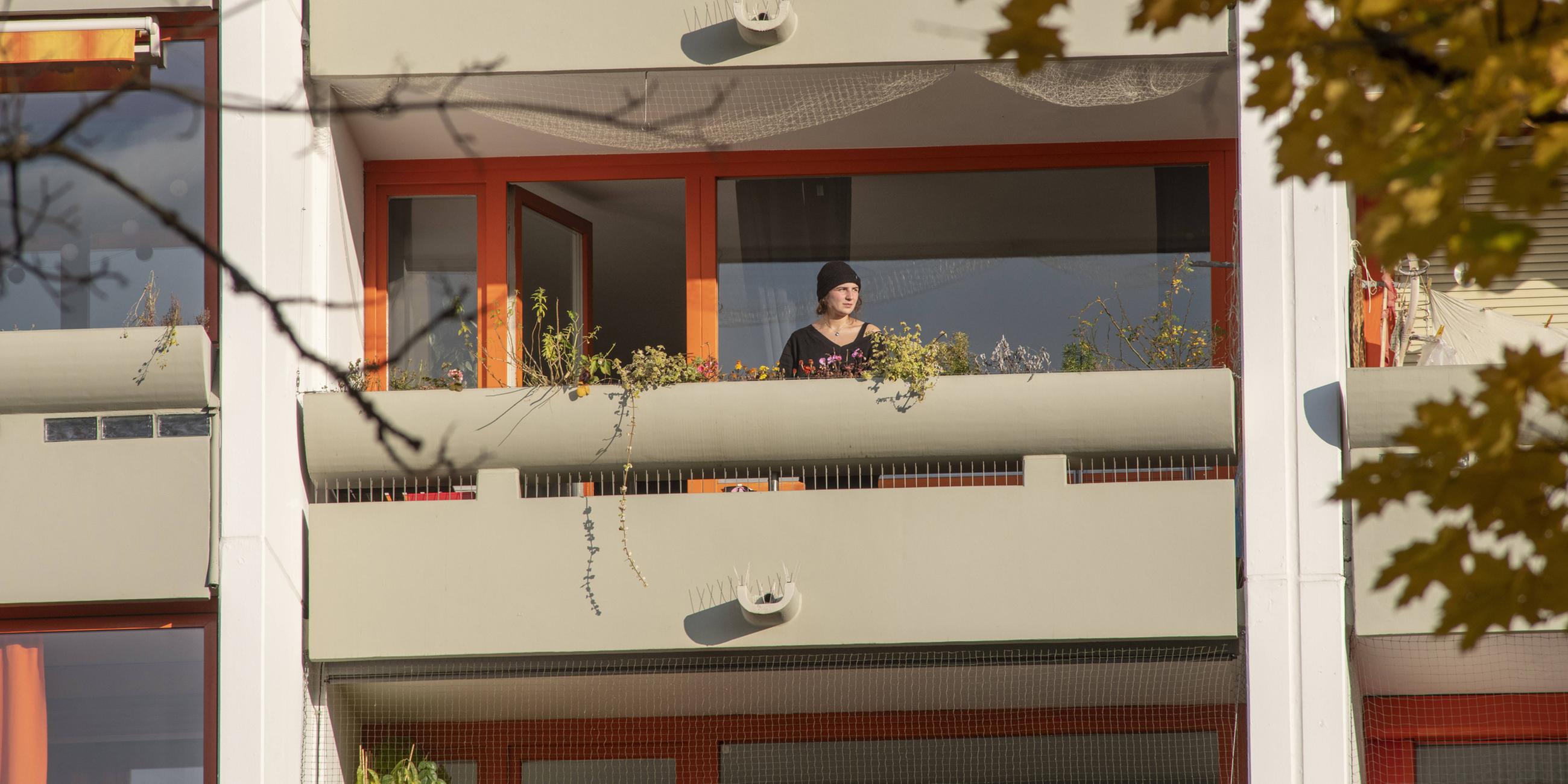 Eine Frau steht auf ihrem Balkon