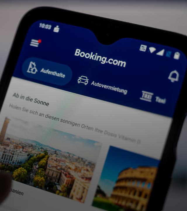 Auf einem Smartphone ist die App des Reiseportals Booking.com zu sehen.