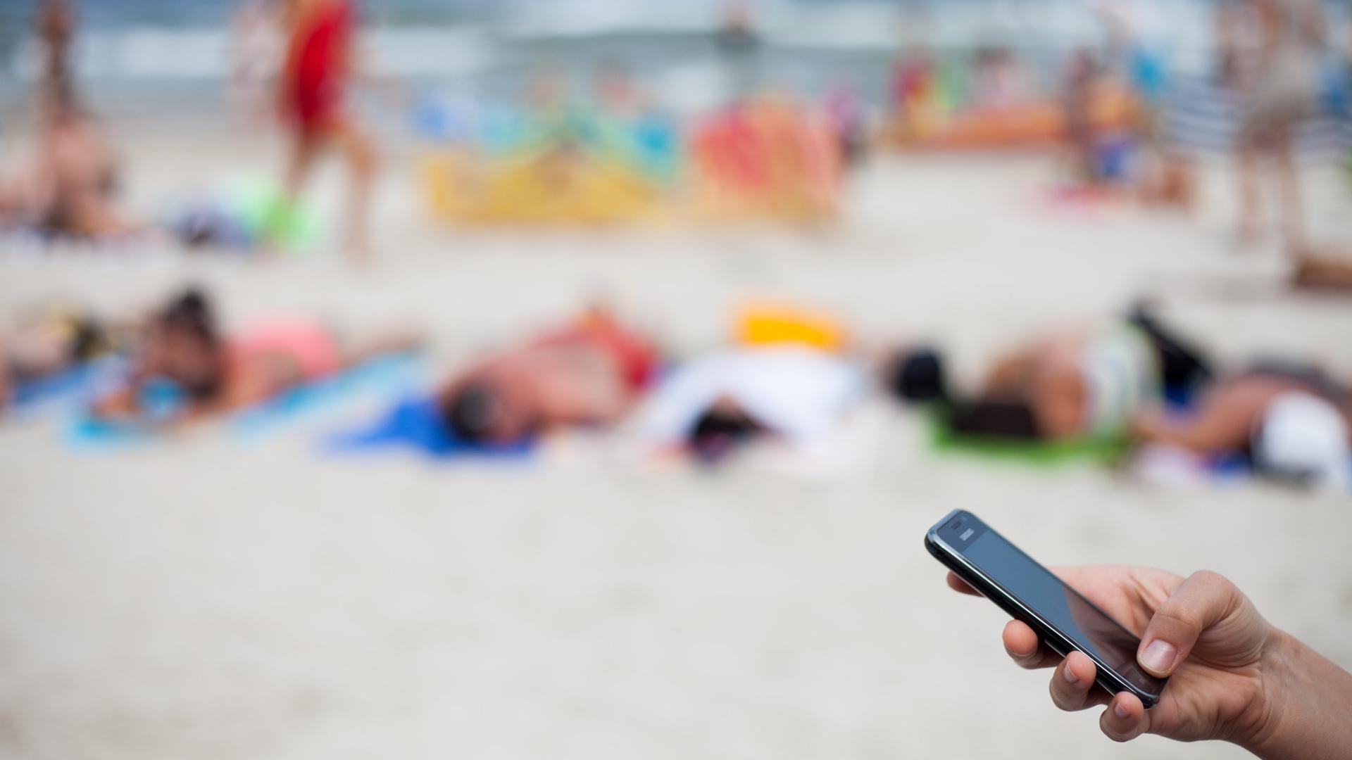 Polen, Kolben: Eine frau hält ein Mobiltelefon am Strand, Archivbild