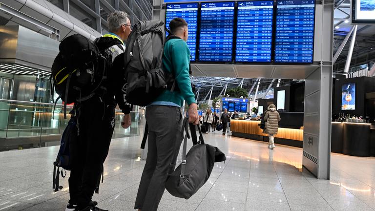 Reisende schieben ihre Koffer am Flughafen Düsseldorf zur Gepäckaufgabe.