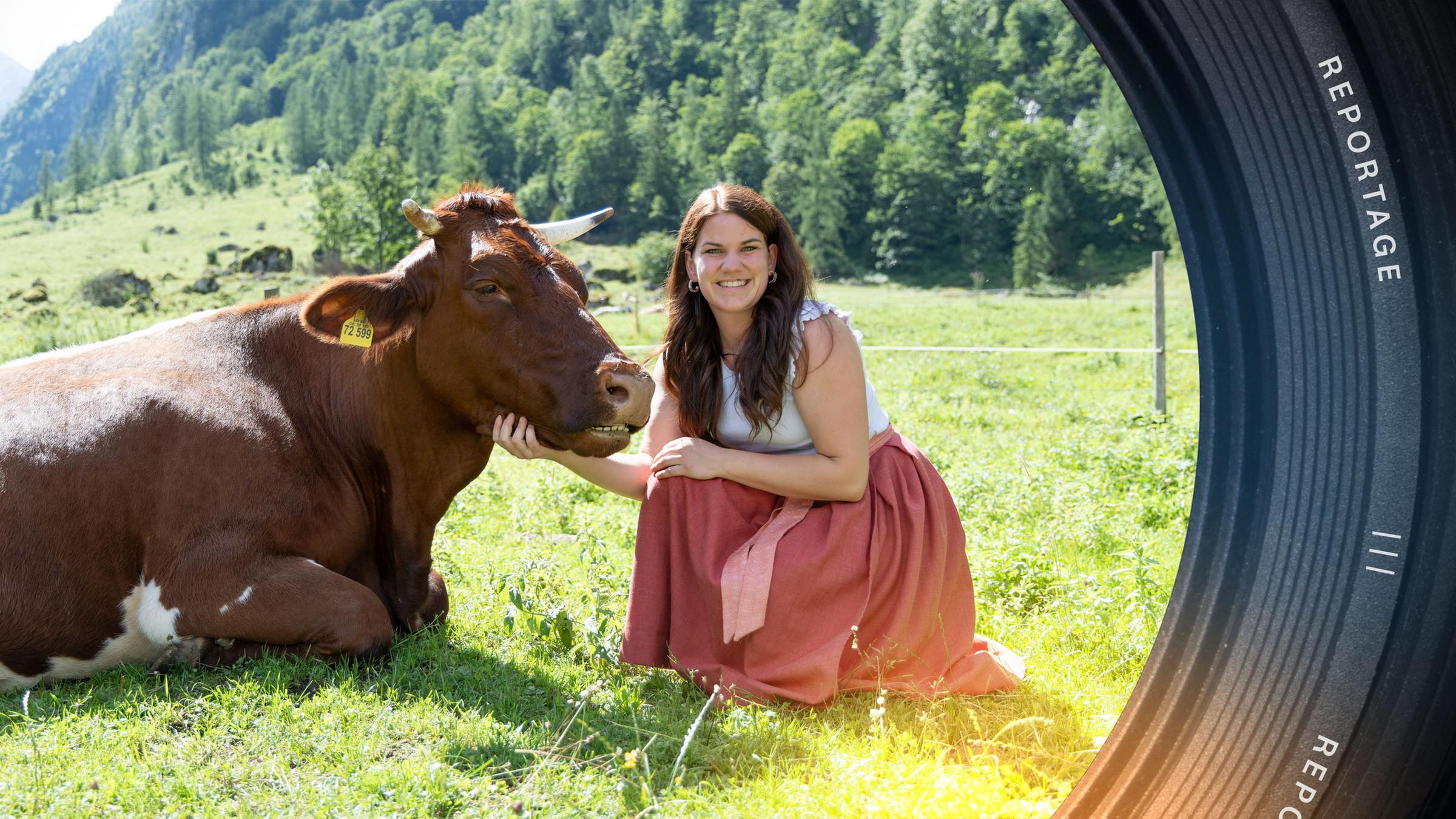 Veronika hockt neben einer liegenden Kuh auf einer Weide und schaut lächelnd in die Kamera.