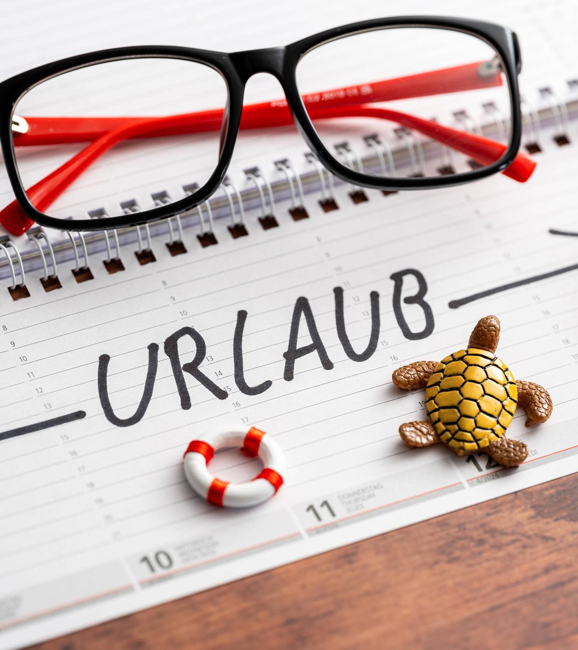 Schrift "Urlaub" auf einem Kalender mit Markierung der ganzen Woche. Liegestuhl und Strandzubehör auf Kalender.